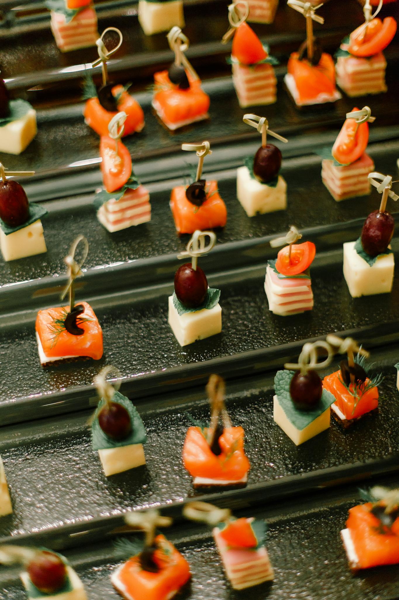 Delicious canapés featuring cheese, cherry tomatoes, and fruit skewers elegantly arranged for a party.